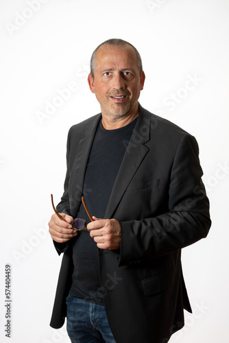 businessman in a casual suit holding glasses in his hands smiling at the camera