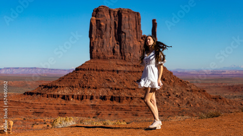 Long-haired girl in white dress on the background of mighty unique famous rock formations in Monument Valley. Navajo Tribal Park, Utah; Arizona, USA.