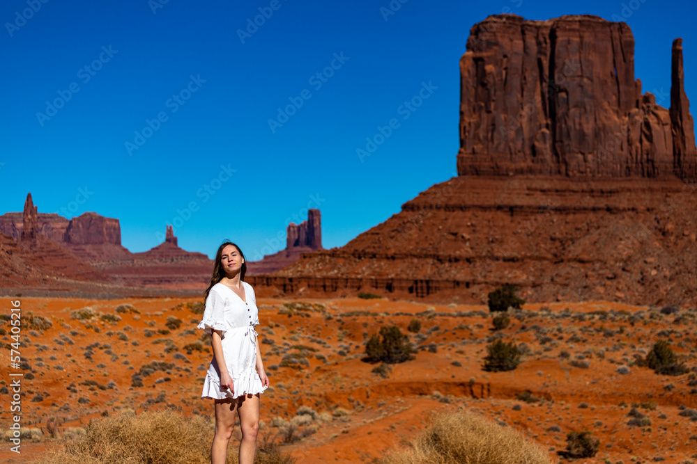 Beautiful long-haired girl in white dress on the background of famous rock formations in Monument Valley. Navajo Tribal Park, Utah; Arizona, USA.