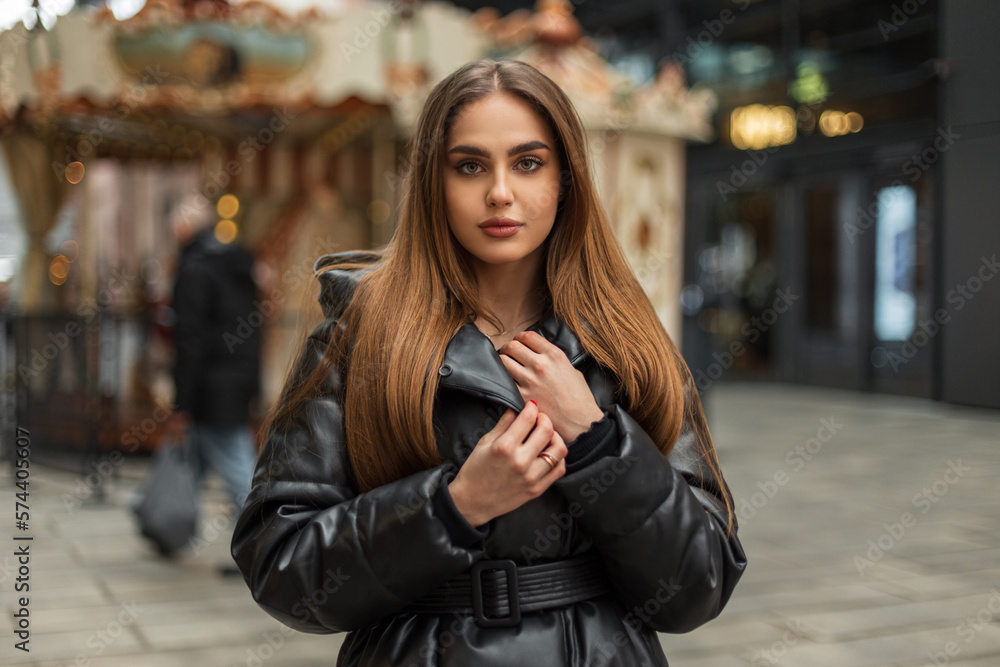 Beautiful female street portrait of a pretty caucasian woman model with green eyes in a winter fashionable black down jacket walking in a vintage park in the city Beautiful female street portrait of a pretty caucasian woman model with green eyes in a winter fashionable black down jacket walking in a vintage park in the city