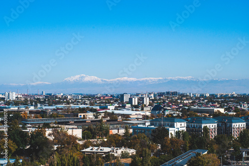 Fototapeta Naklejka Na Ścianę i Meble -  View of Tashkent, the outskirts of the city, the country of Uzbekistan. View of the mountains and residential buildings from the window. Sunny day.