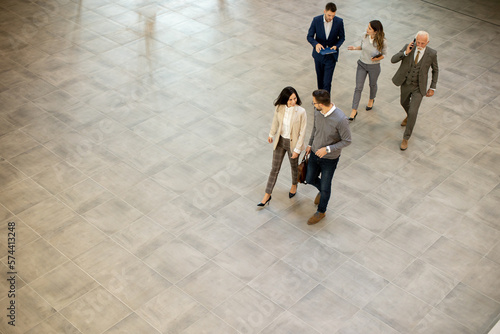 Fotografía A group of young and senior business people are walking in an office hallway, captured in an aerial view