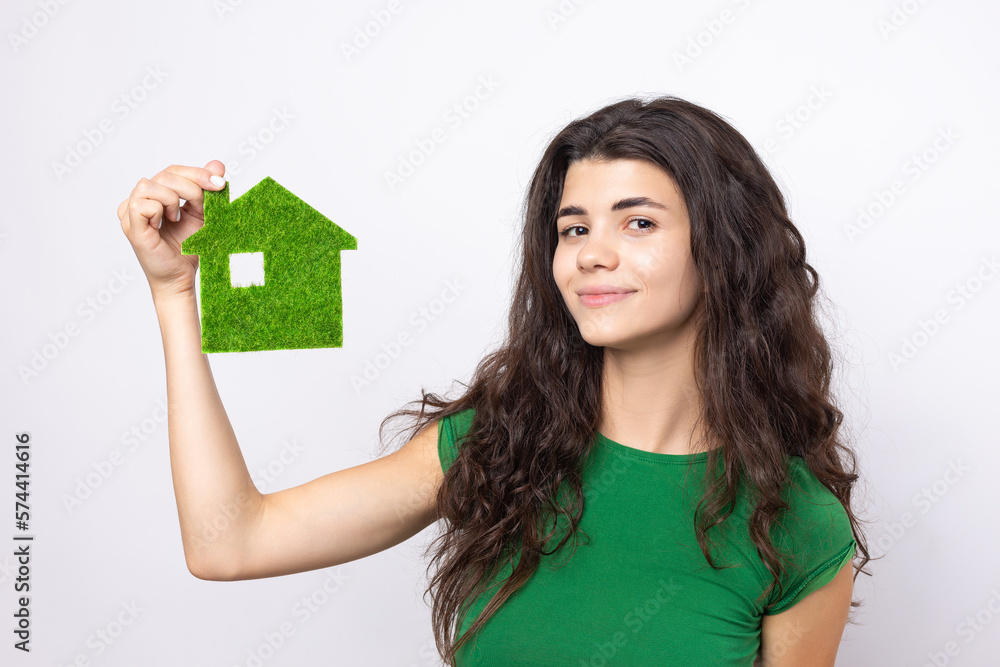 Happy house buyer. A young girl holds a model of a green house in her hands. The concept of green energy, ecology. Happy house buyer. A young girl holds a model of a green house in her hands. The concept of green energy, ecology.