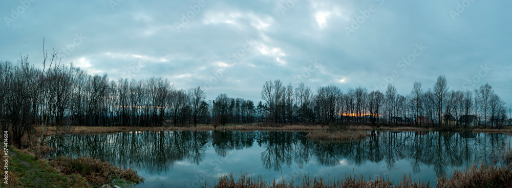 Panoramic photo during steel hour on an almost windless evening with a smooth lake.