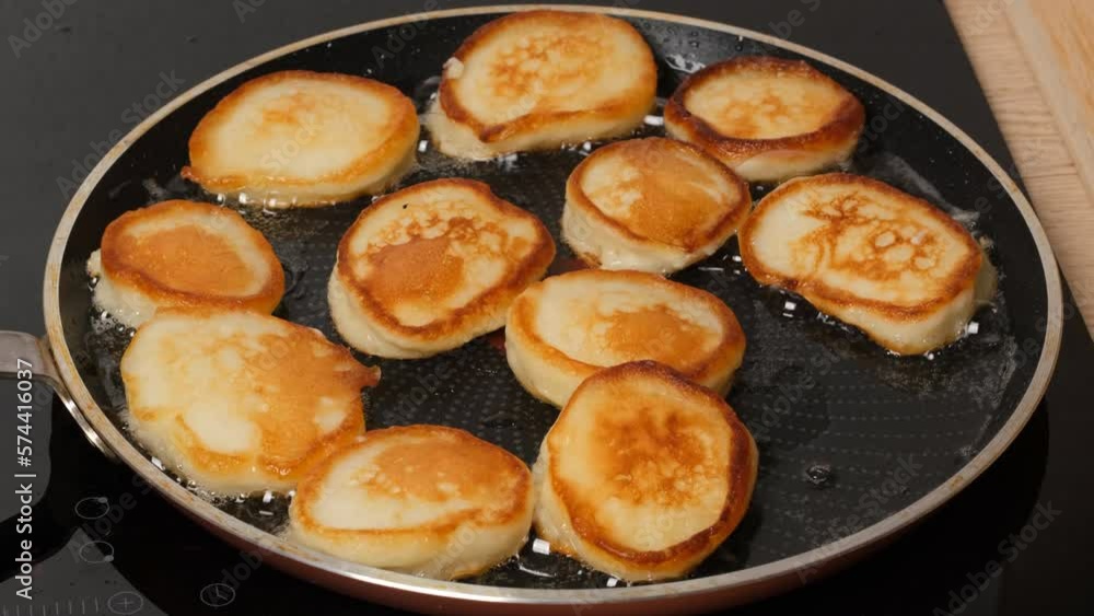 The cook prepares small pancakes in a frying pan. Healthy food concept. The cook prepares small pancakes in a frying pan. Healthy food concept.