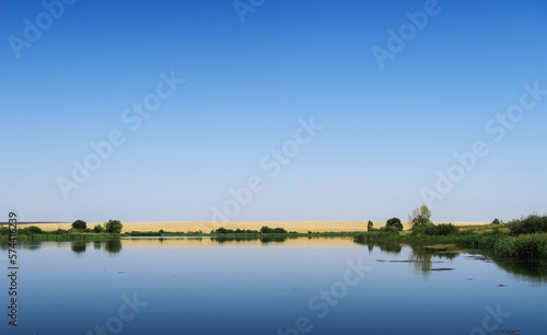 Fototapeta Naklejka Na Ścianę i Meble -  Reflection of the sky with clouds on the shore of a large lake on a sunny summer day.