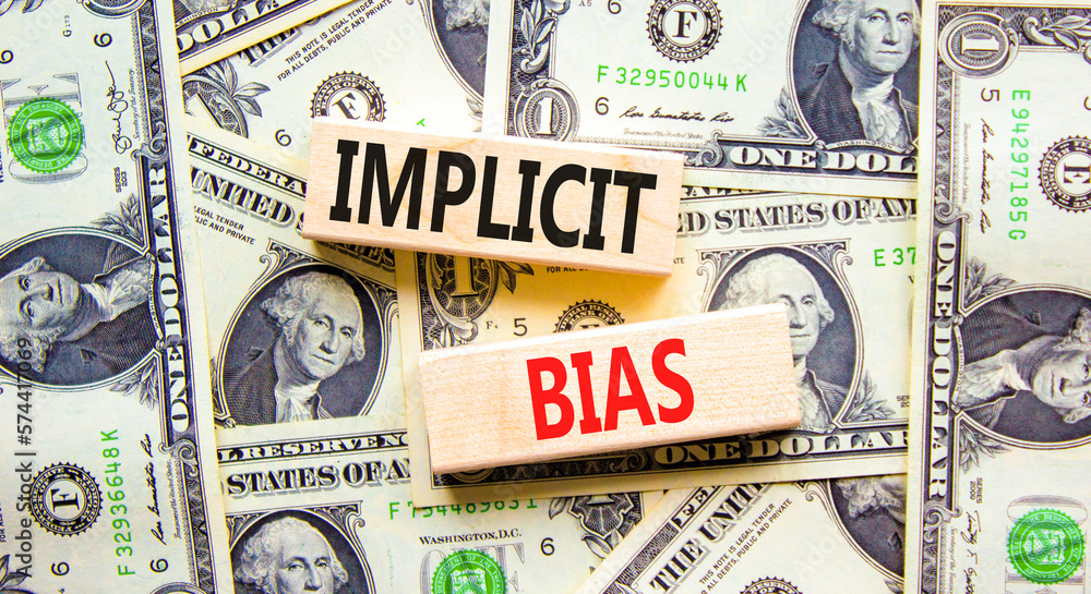 Implicit bias symbol. Concept words Implicit bias on wooden block. Beautiful background from dollar bills. Dollar bills. Business psychology implicit bias concept. Copy space.