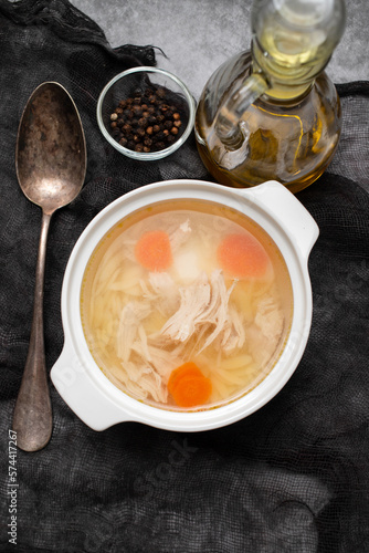 bowl of chicken broth with chicken and carrot in dark