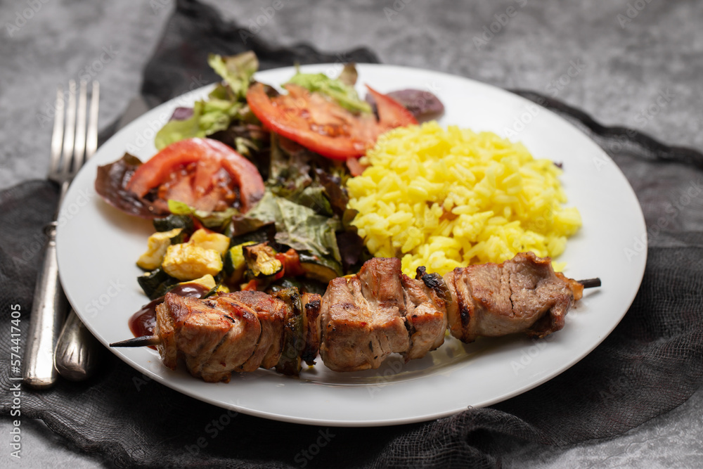 Grilled meat on stick, vegetables, salad and boiled rice