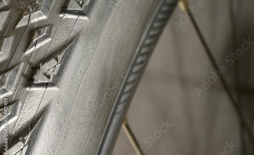 Close-up of a new bicycle tire with the wheel’s spokes out of focus in the background. 