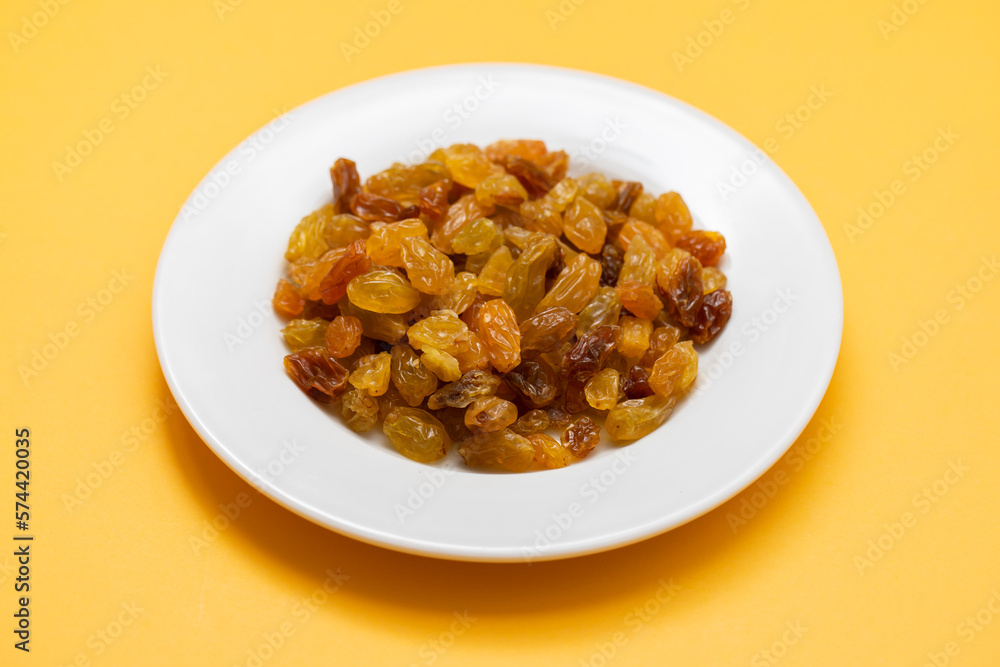 Yellow golden raisins in white ceramic plate Yellow golden raisins in white ceramic plate
