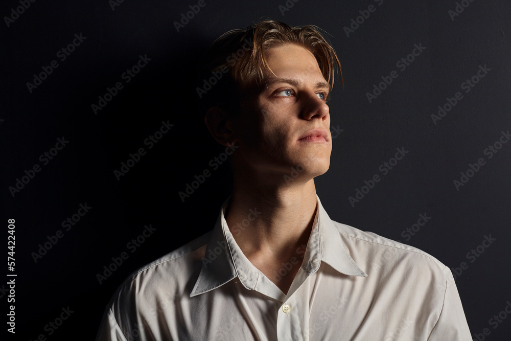 portrait of a handsome man in a white shirt on a black background, looking seriously at the camera portrait of a handsome man in a white shirt on a black background, looking seriously at the camera