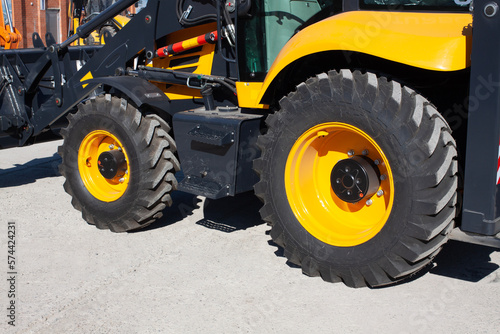 Rubber large black wheels with a raised surface. Car tread of road construction backhoe loader.