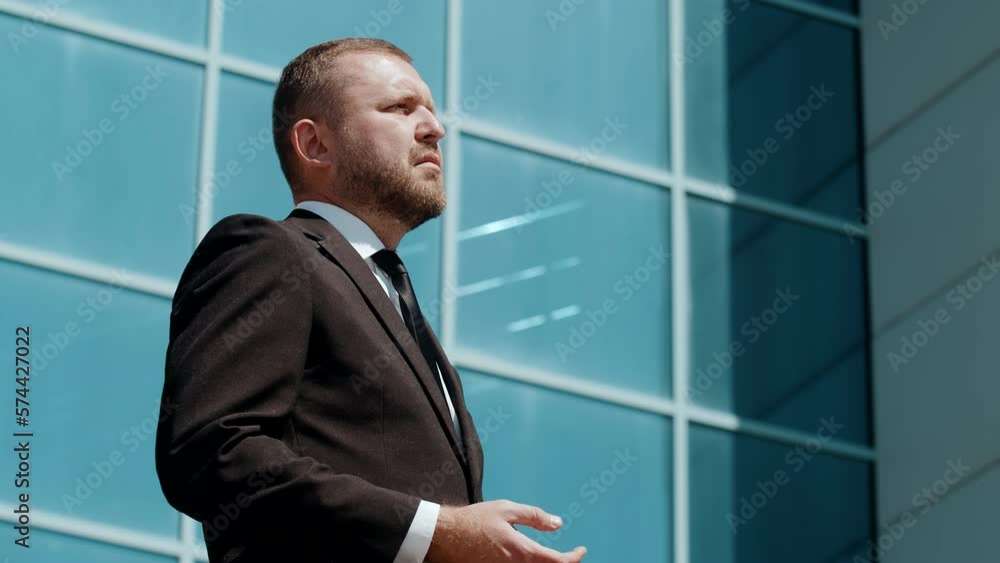 Close-up outdoor portrait of confident middle aged bearded business man in suit posing outdoor with folded arms, looking aside near office building. Successful career, corporate Close-up outdoor portrait of confident middle aged bearded business man in suit posing outdoor with folded arms, looking aside near office building. Successful career, corporate