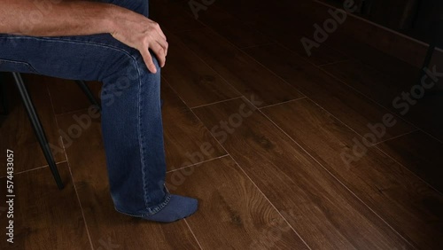 male white hand on knee while leg repeatedly uncontrollably shakes up and down due to restless leg syndrome. perhaps a sign of being deep in thought or tired of waiting for what he wants