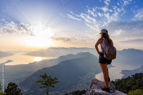 Happy girl with a backpack is on the edge of a high mountain in Montenegro