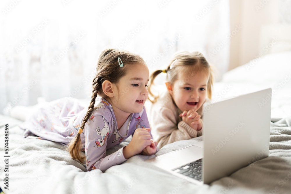 Two girls sisters watching on laptop. Technology and home concept. Two girls sisters watching on laptop. Technology and home concept.