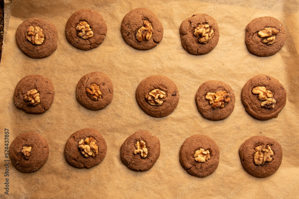 Fototapeta premium Warm vegan walnut and chocolate cookies on parchment paper with top down composition