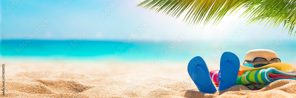 Summer holiday background with flip flops and palm tree on sandy beach