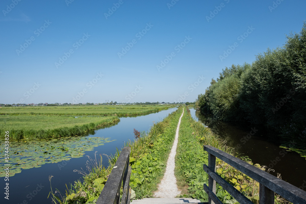 Typical Dutch rural scenery showing the flat Netherlands. canal water is part of a flood management system for the polder which is land reclaimed from the sea and converted into arable farm fields