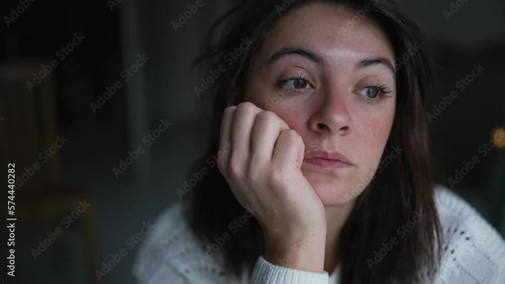One pensive woman scratching face at home while thinking about life staring out apartment window One pensive woman scratching face at home while thinking about life staring out apartment window