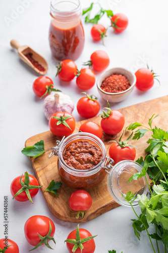 Salsa sauce is a traditional Mexican sauce with tomatoes and hot peppers on a light background with fresh herbs close up. Concept of a vegetarian food.