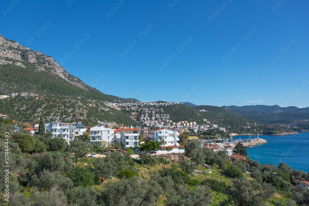 Majestic panoramic view of seaside resort city of Kas in Turkey. Hillside with traditional houses in the city, Villas and hotels with red roofs are open for tourists.