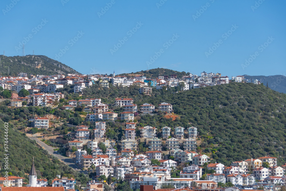 Majestic panoramic view of seaside resort city of Kas in Turkey. Hillside with traditional houses in the city, Villas and hotels with red roofs are open for tourists.