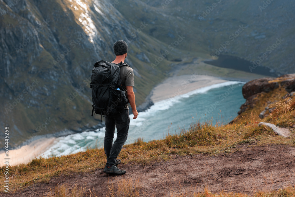 Man with backpack looking into the distance while hiking on a trail in Norway