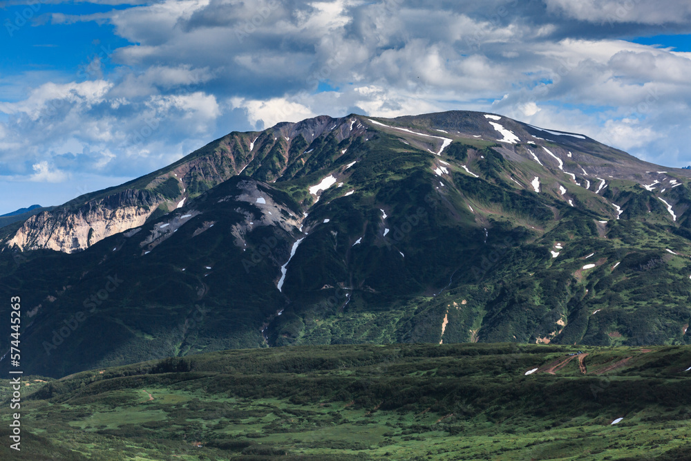 Obraz premium Green mountains interspersed with snow, landscape, clouds, sun, Kamchatka.