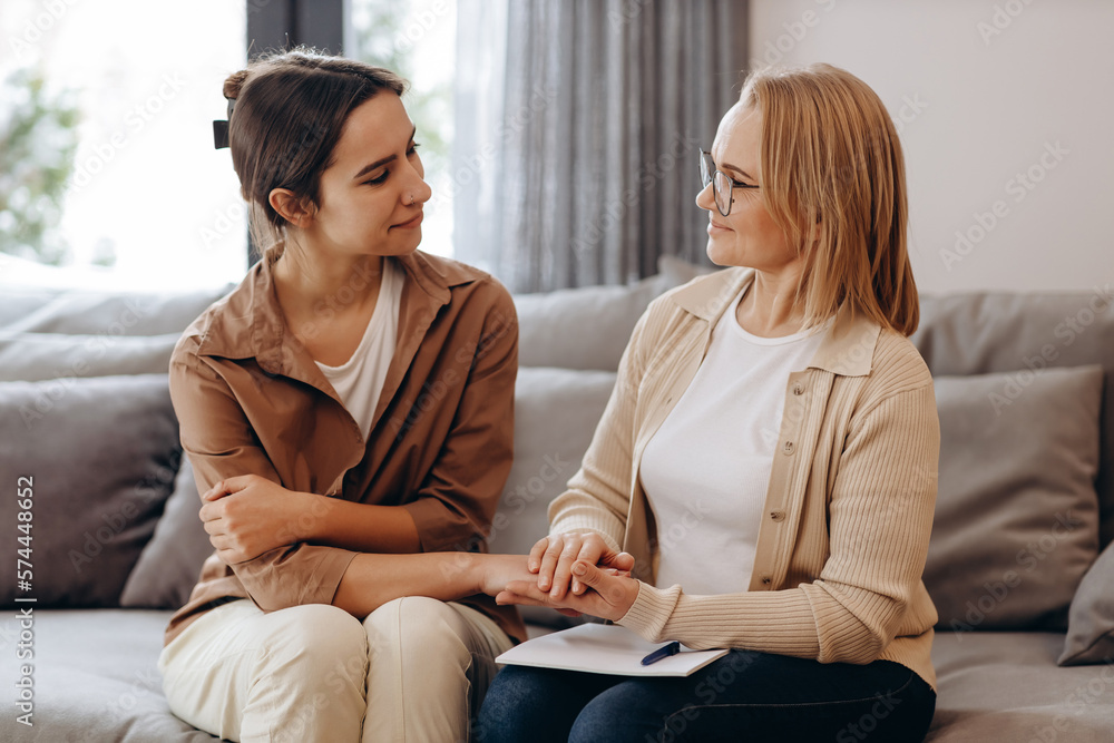 The girl came for a consultation with a psychologist, the psychologist and the client look at each other, and the psychologist holds the client's hand in a gesture of support. The girl came for a consultation with a psychologist, the psychologist and the client look at each other, and the psychologist holds the client's hand in a gesture of support.