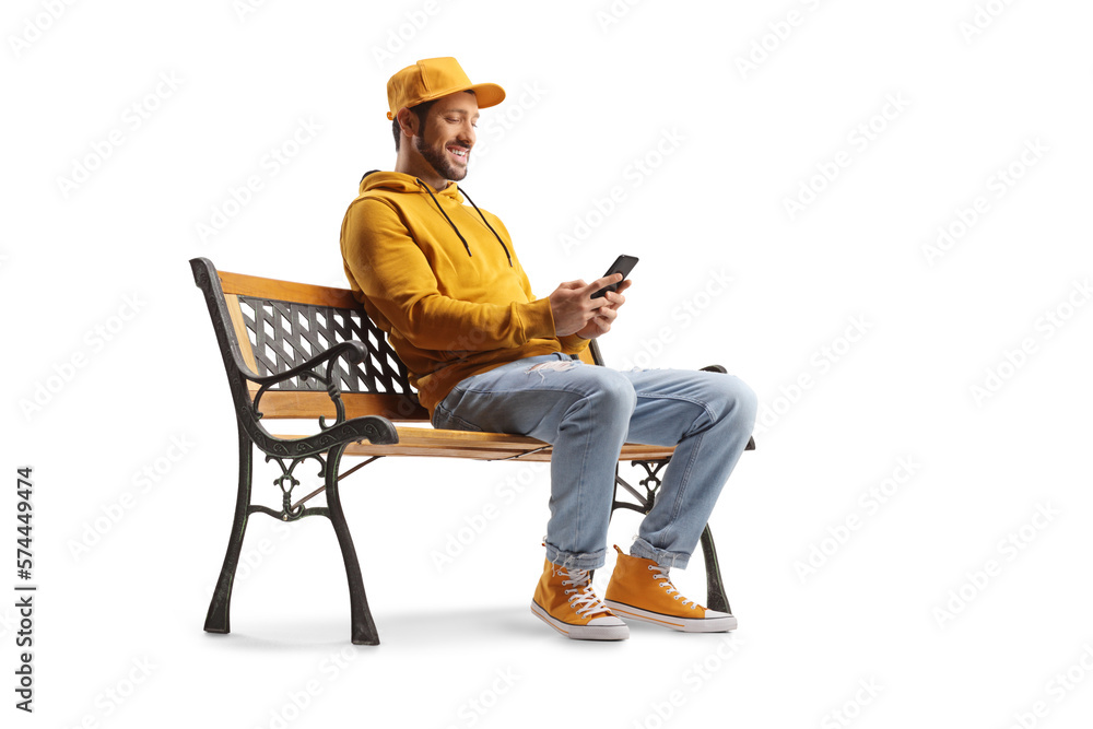 Cheerful guy sitting on a bench and using a smartphone