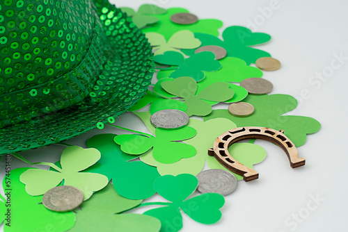 St. Patrick's Day concept. Mockup, layout of green clover, shamrock on white background and green hat with wooden horseshoe and coins Close-up.