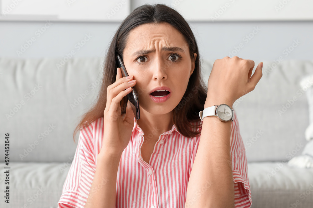 Worried young woman with wristwatch talking by mobile phone at home, closeup Worried young woman with wristwatch talking by mobile phone at home, closeup