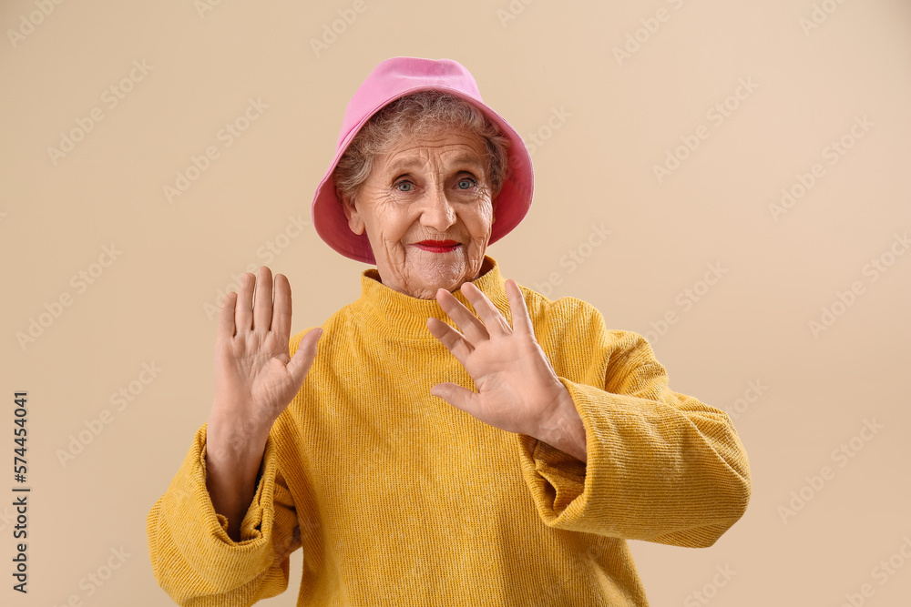 Senior woman in bucket hat on beige background Senior woman in bucket hat on beige background