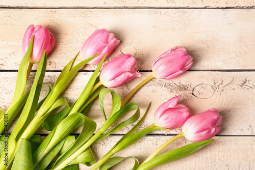 Beautiful tulip flowers on beige wooden background