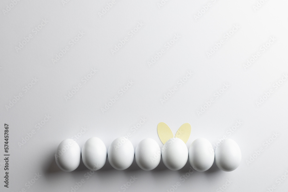Naklejka premium Image of row of white easter eggs with bunny ears and copy space on white background