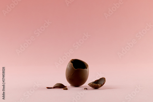 Image of broken chocolate easter egg and copy space on pink background