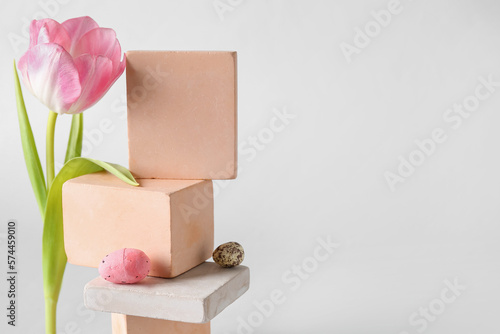 Composition with podiums, tulip flower and Easter eggs on white background, closeup