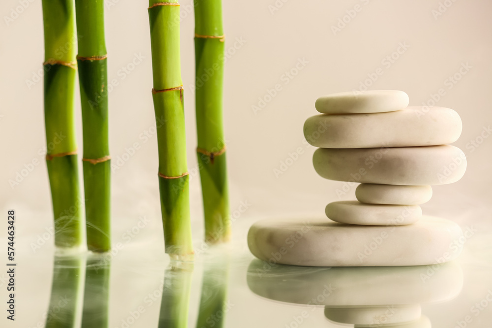Stack of spa stones and bamboo on light background
