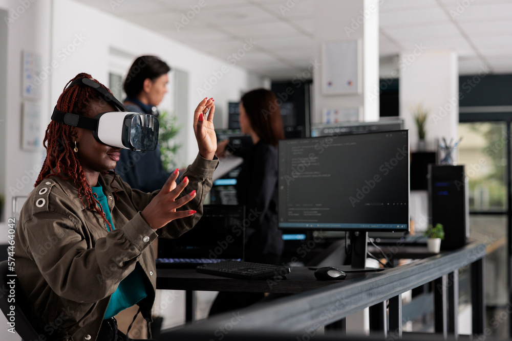African american system engineer wearing virtual reality goggles working to develop security program in it big data office, software developer with vr headset coding html script with database. African american system engineer wearing virtual reality goggles working to develop security program in it big data office, software developer with vr headset coding html script with database.