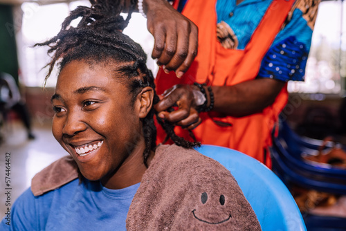 A young queer masculine woman retwisting her dreadlocks