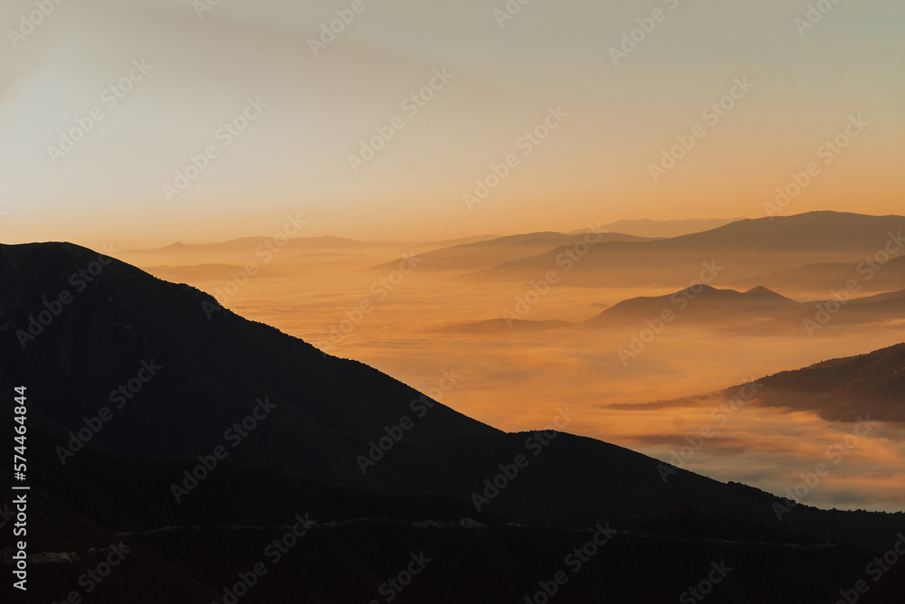Mountain range with visible silhouettes through the morning colorful fog Mountain range with visible silhouettes through the morning colorful fog