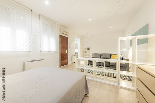 Fotografia Loft-style apartment furnished with white wooden shelves, chest of drawers, armo