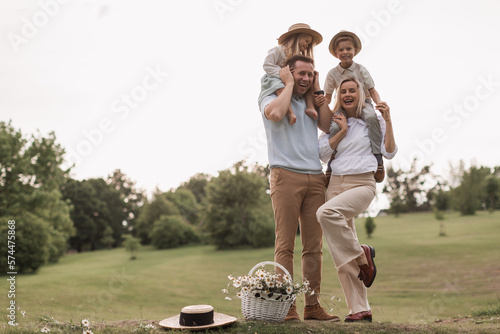 Children, dad and mom play in meadow in sunshine. mother, father and little daughter with brouther walking in field in the sun. Happy young family. concept of a happy family. photo