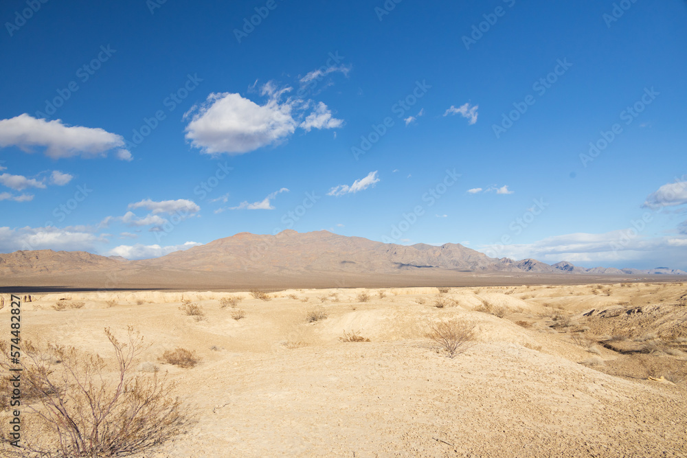 Desert landscape with mountain background and blue sky with white clouds

