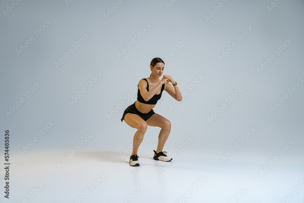 Fitness woman doing deep squat exercise on studio background. Workout Concept. High quality photo Fitness woman doing deep squat exercise on studio background. Workout Concept. High quality photo
