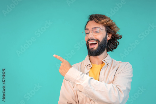 Confident young man pointing aside with finger hand gesture at copy space isolated color background