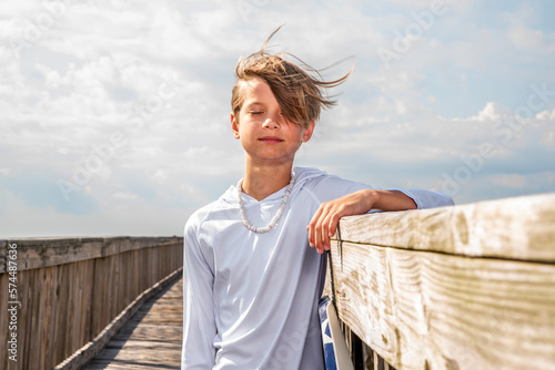 Young Preteen Boy Standing with his Eyes Closed On A Boadwalk photo