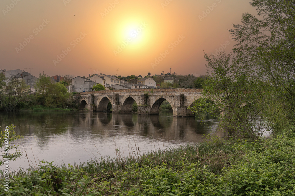 Spectacular sunset overlooking the Roman bridge and the river Miño as it passes through Lugo with the orange sky with haze. Lugo, Galicia, Spain.